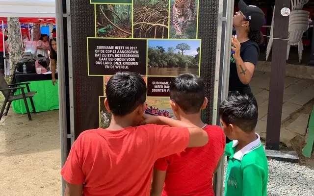Children reading the Forest93 information totem at the Amazonemarkt in Paramaribo's Palm Garden