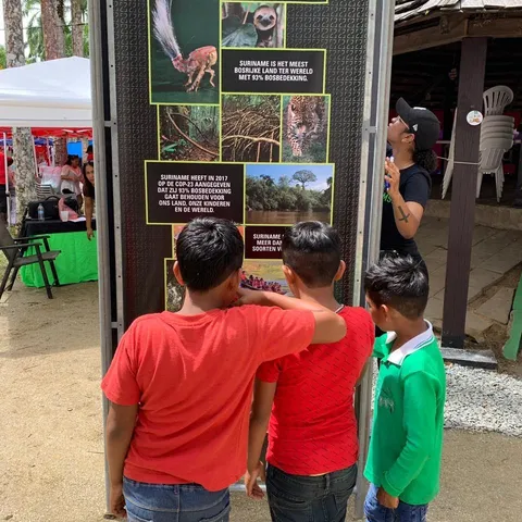 Children reading the Forest93 information totem at the Amazonemarkt in Paramaribo's Palm Garden