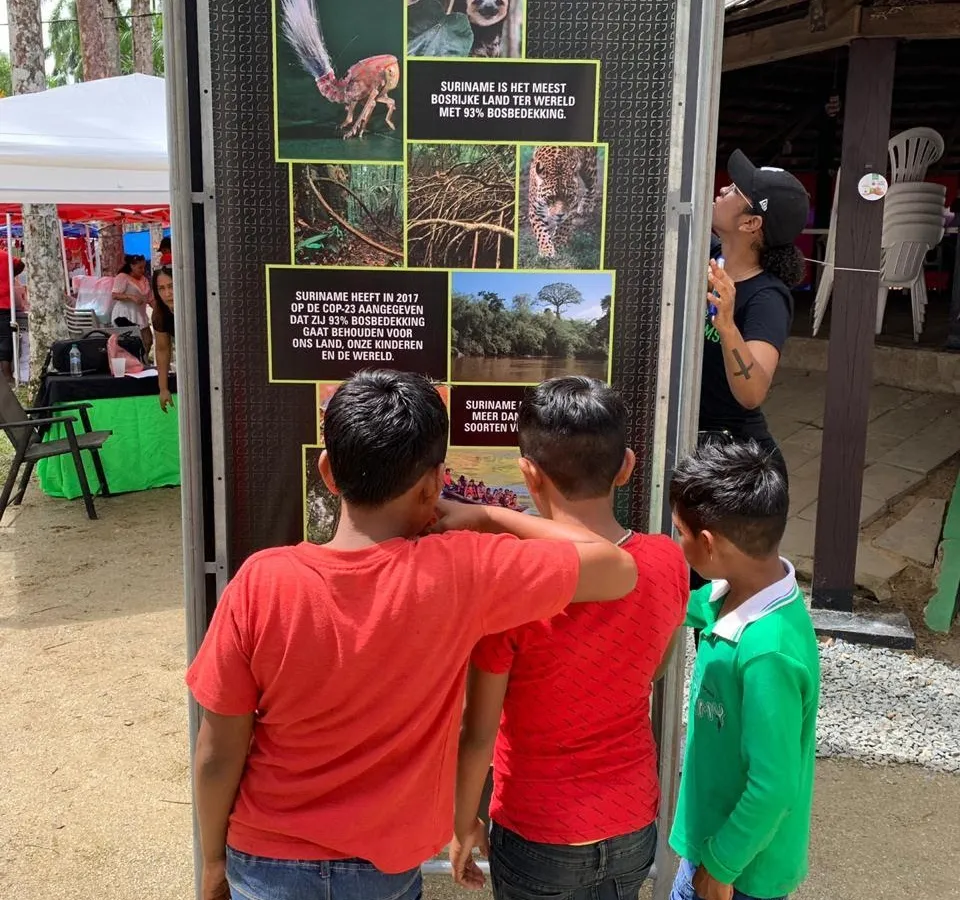Children reading the Forest93 information totem at the Amazonemarkt in Paramaribo's Palm Garden