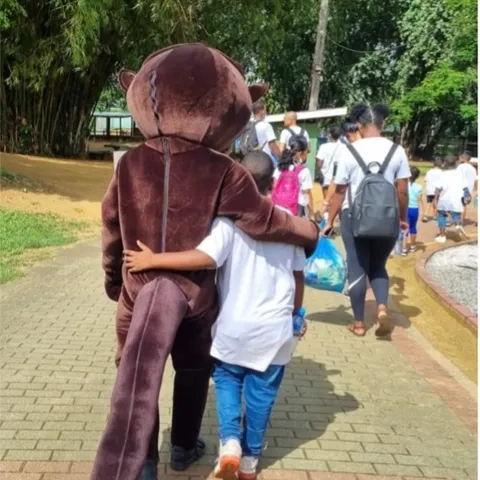 Bollie the Otter walking arm in arm with a child at a clean-up event