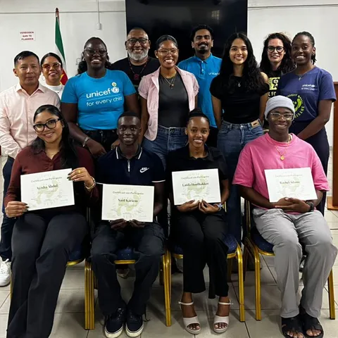 The 2026 Plastic Footprint Agents at their graduation ceremony, four of them seated at the front holding their certificates of participation, with trainers and UNICEF staff standing behind them