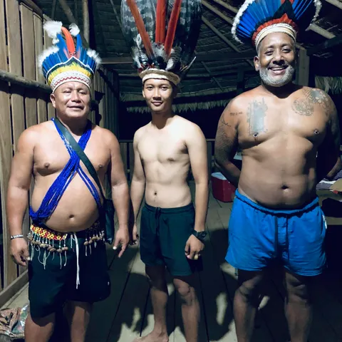 Three men wearing feathered headdresses and beaded sashes
