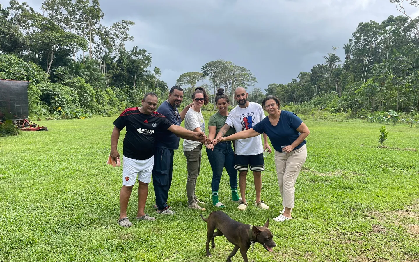 The planting group standing together on the grassy plot in Saramacca, with a dog in front