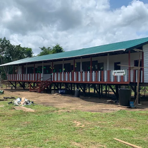 De afgebouwde school in Amatopo, een lang houten gebouw op palen met een groen dak