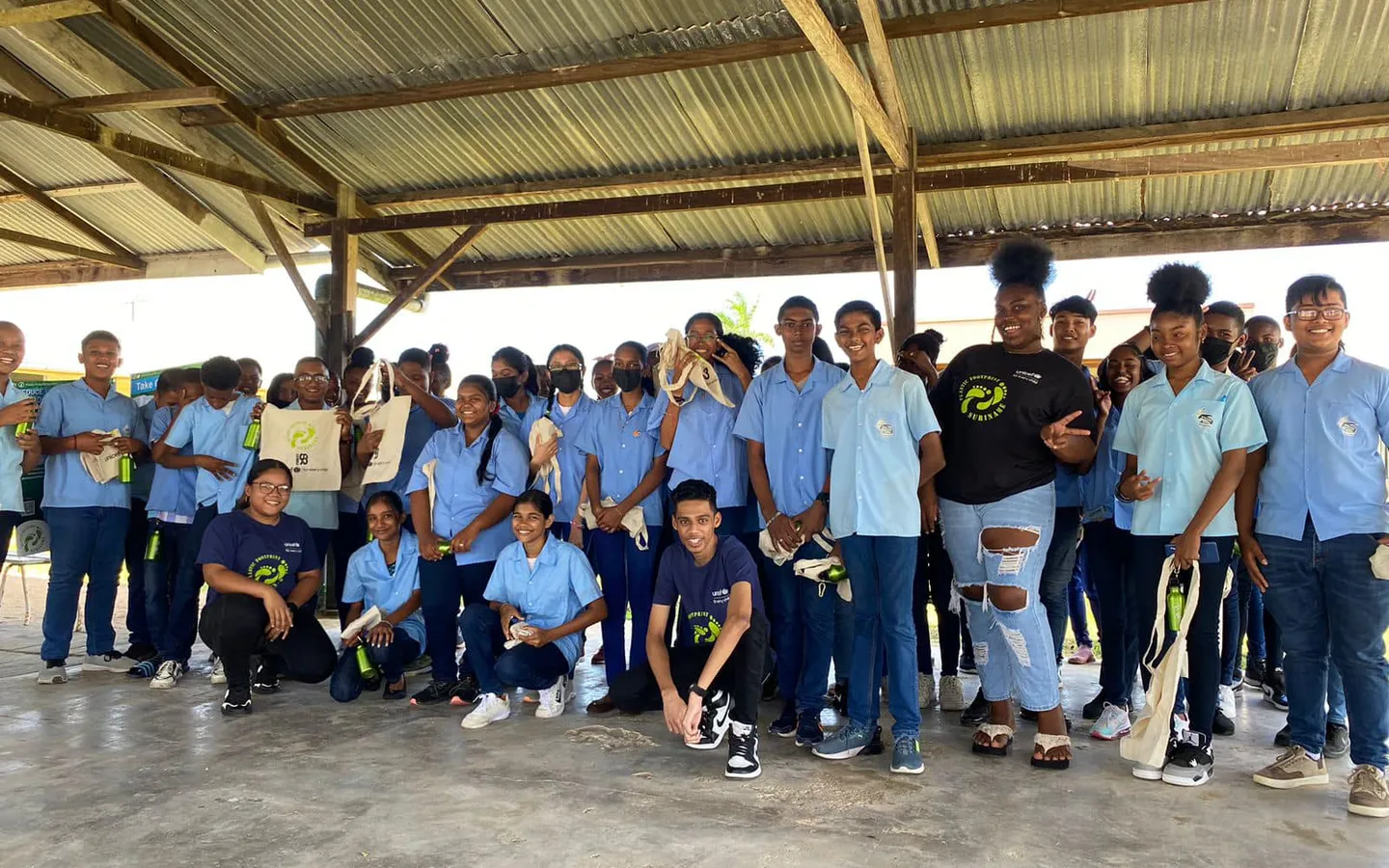 A large group of secondary school students in uniform gathered under a school canopy after a session
