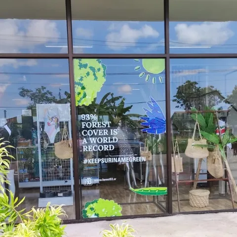 A shop window decorated with the campaign artwork: a green map of Suriname, a macaw, a caiman and the line "93% forest cover is a world record"