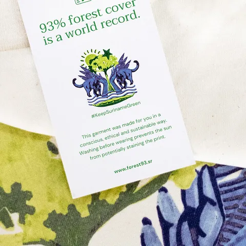 The swing tag on the t-shirt, carrying the campaign line, the #KeepSurinameGreen hashtag and a note that the garment was made in a conscious, ethical and sustainable way
