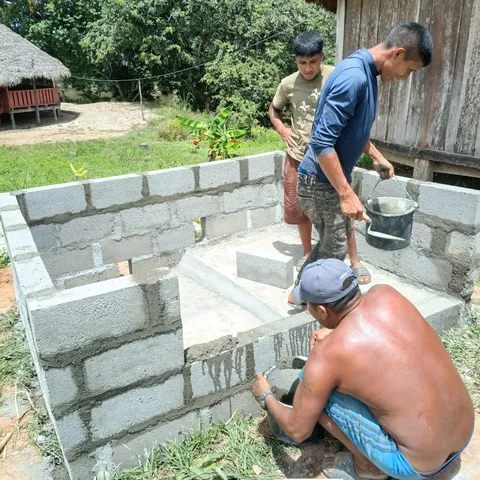 Three men of the local work team laying concrete blocks and pointing the mortar on a bathroom under construction near the guesthouse